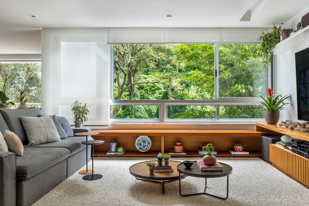 Sala de tv com sofá azul e mesas de centro