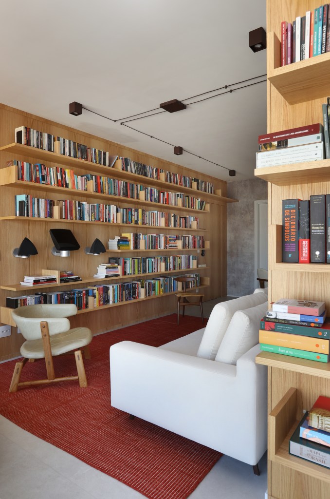 02-como-decorar-a-casa-com-livros-Projeto Aie Tombolato – Foto Mariana Orsi Sala de estar; estante; livros; poltrona; sofá branco; tapete vermelho