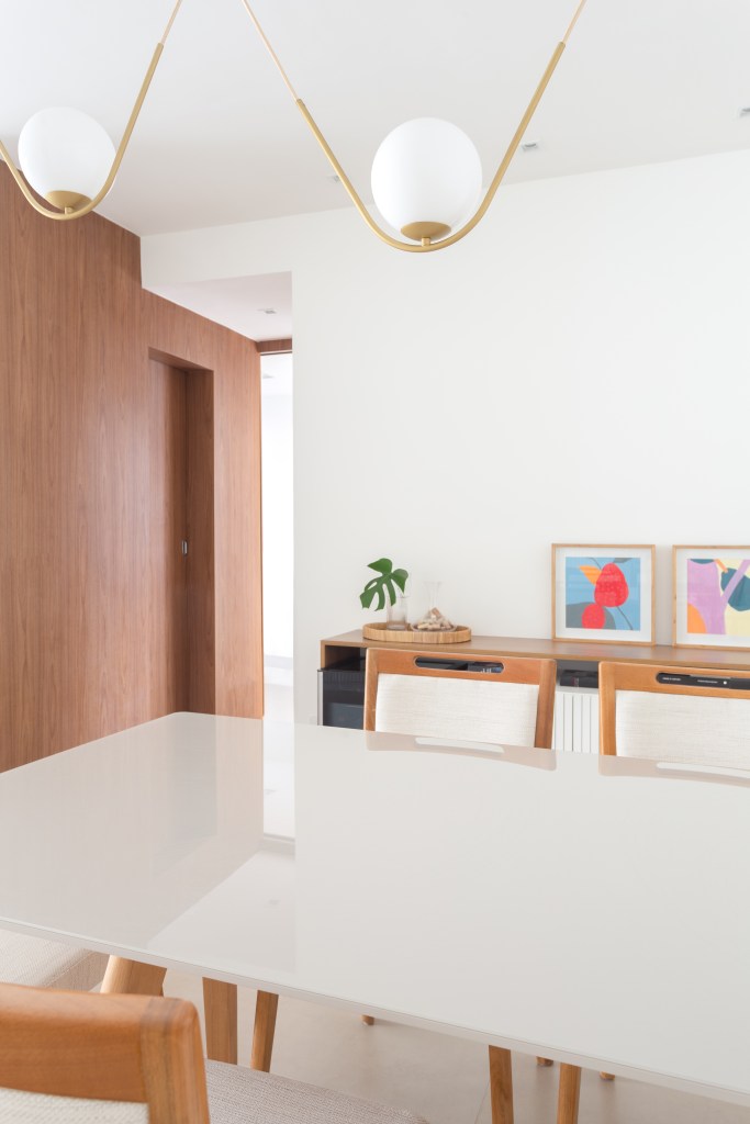 Sala de jantar; sala de jantar branca; mesa branca; luminária esférica pendente; cadeira de madeira