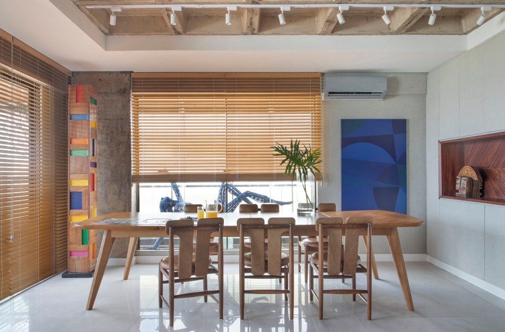 ape-160m-paineis-madeira-ripada-sofa-verde-design-nacional-roby-studio-arquitetura-06-sala-jantar Sala de jantar com mesa e cadeiras de madeira; quadro azul na parede