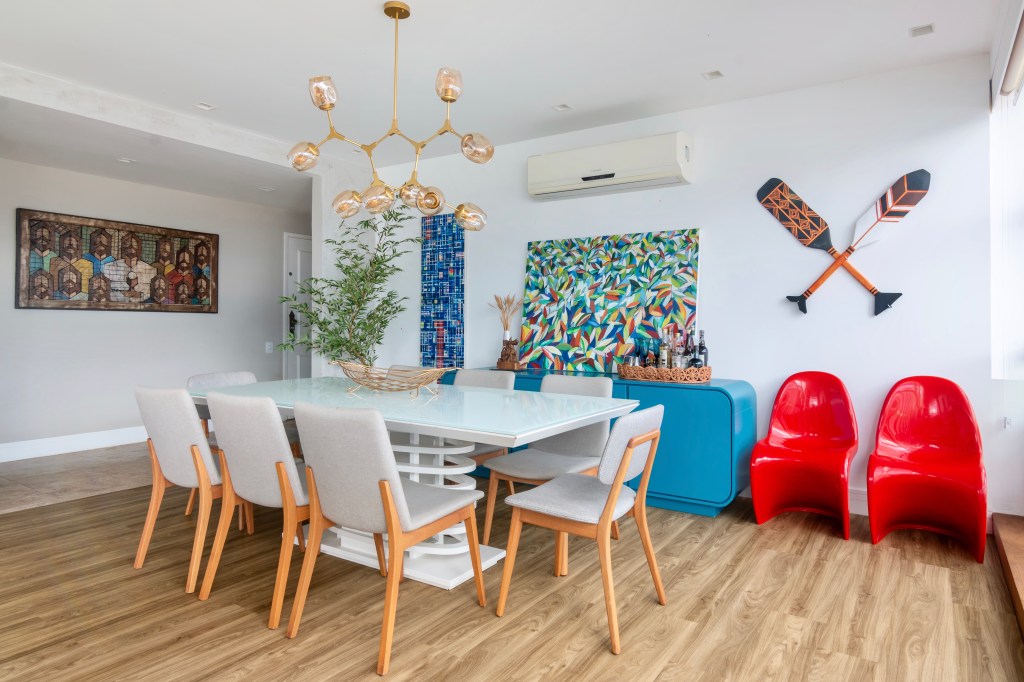 Sala de jantar com piso vinilíco, buffet azul, mesa com tampo branco e lustre.