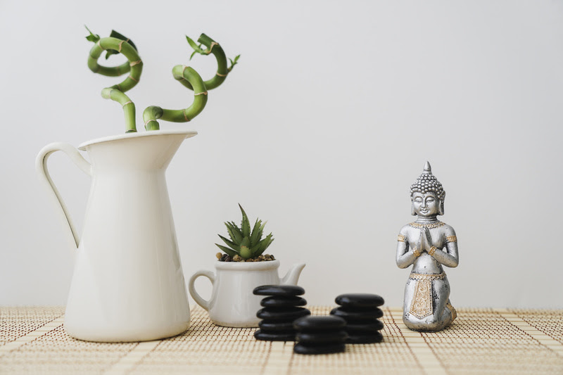 Mesa de madeira com estátua de buda, vaso de suculenta e bambu da sorte