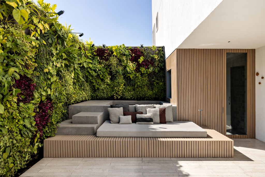 Terraço com deck de madeira e sofá; jardim vertical.