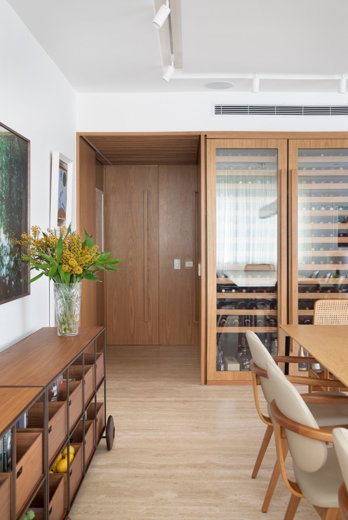 Sala de jantar com mesa de madeira e cadeiras de madeira; adega em marcenaria.