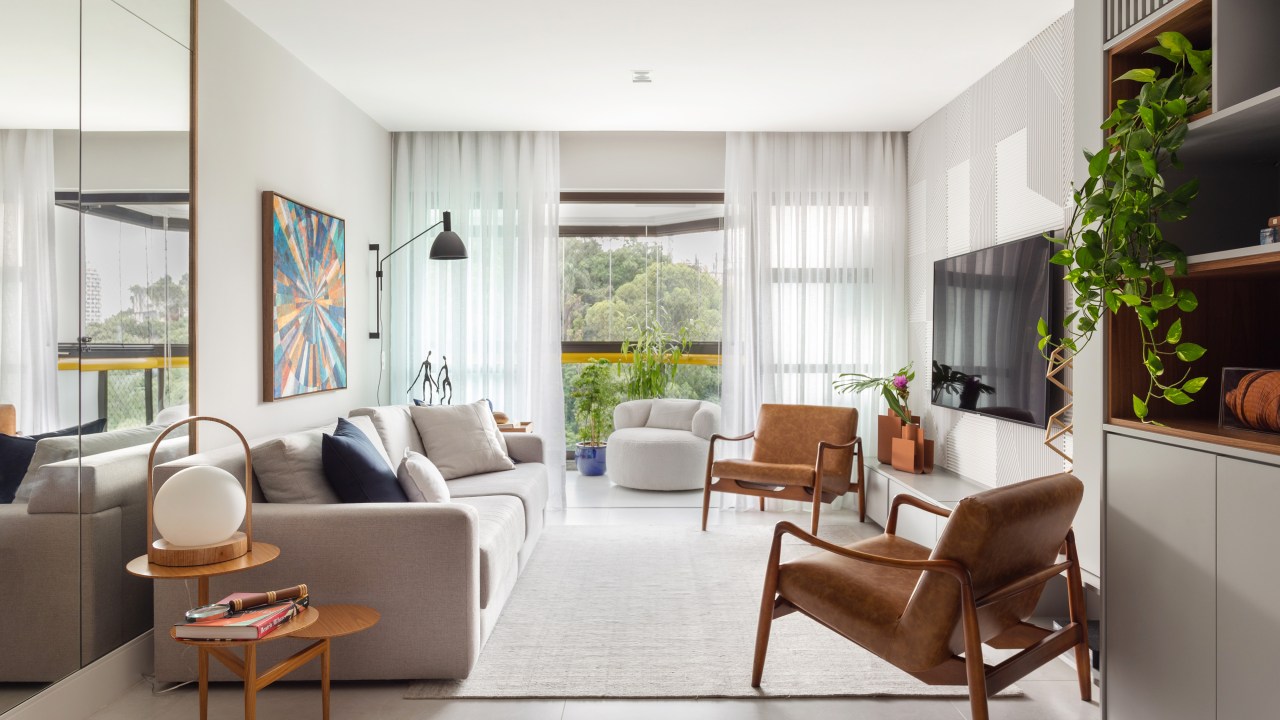 Sala de estar neutra com sofá branco, poltronas e tapete claro.