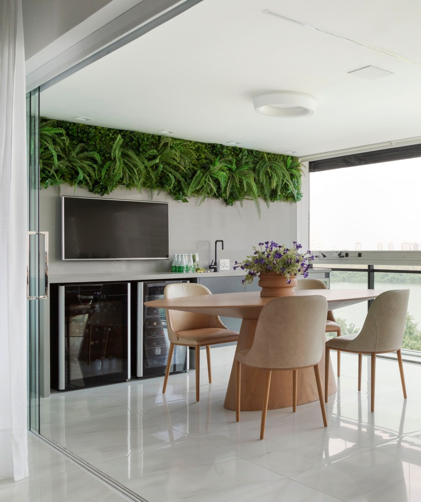 reforma-ape-270m-sala-intima-brinquedoteca-home-office-paula-muller-09-varanda-integrada Varanda integrada com área gourmet, piso de porcelanato, mesa redonda, adega e bancada.