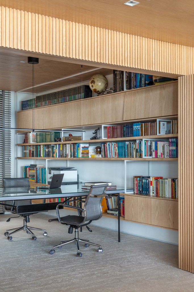 reforma-cria-coworking-sala-intima-ape-320m-up3-arquitetura-08-home-office Home office; Espaço de coworking com mesa de trabalho, cadeiras de escritório, estante de madeira com livros.