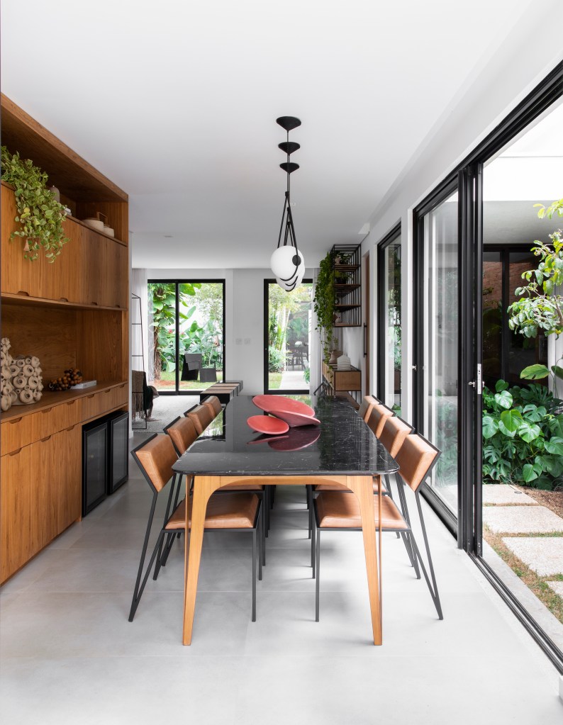 Sala de jantar com mesa de tampo preto e porta de vidro para jardim.