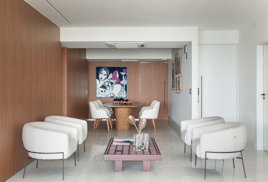 base-neutra-branca-area-social-integrada-123m-roby-macedo-05 Sala de estar integrada com jantar com piso de porcelanato, poltronas brancas e mesa de centro.