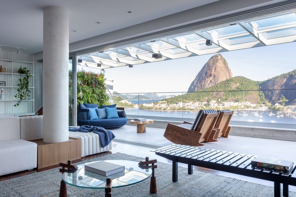 Varanda com vista para Pão de Açúcar; poltronas e sofá azul e jardim vertical.