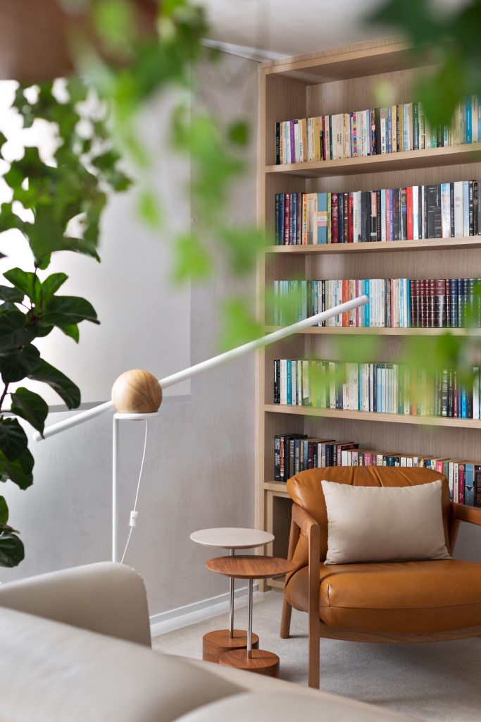 ape-210m-visual-clean-moveis-madeira-plantas-suspensas-archilab-17-leitura-estante-livros Cantinho de leitura com poltrona de couro, luminária de piso e estante de livros.