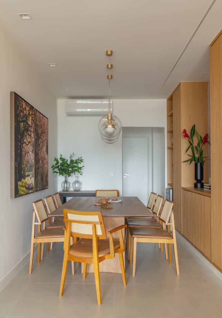 Sala de jantar estreita com mesa e cadeiras de madeira e luminárias.