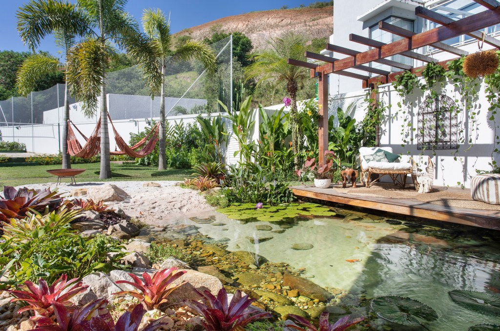 Jardim com lago de peixes, pergolado e redário.