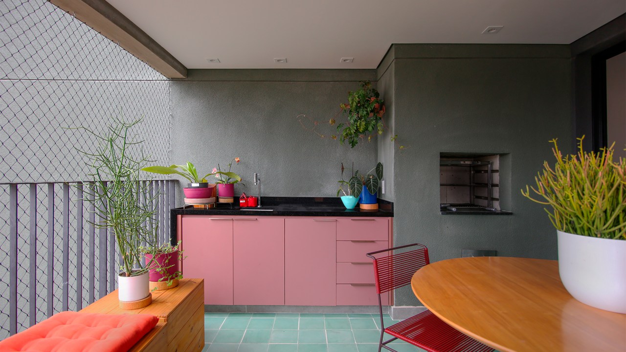 Ladrilho hidráulico cria unidade visual neste apartamento de 140 m². Projeto do Studio MEMM. Na foto, varanda com marcenaria rosa e churrasqueira.