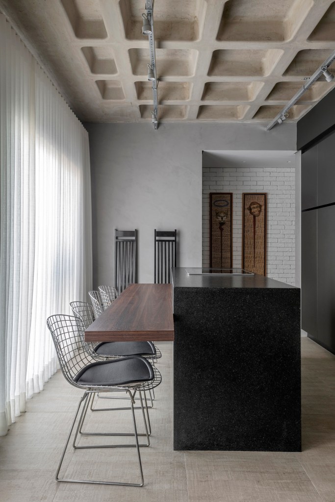 loft-duplex-compacto-64m-decor-industrial-arte-piacesi-arquitetos-04 Cozinha com marcenaria preta, ilha com marcenaria preta e bancada de refeições; piso de porcelanato.