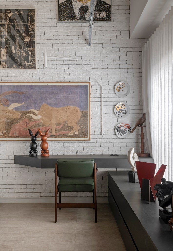 loft-duplex-compacto-64m-decor-industrial-arte-piacesi-arquitetos-11 Home office pequeno com bancada cinza, cadeira estofada verde e parede de tijolinhos brancos com quadros.