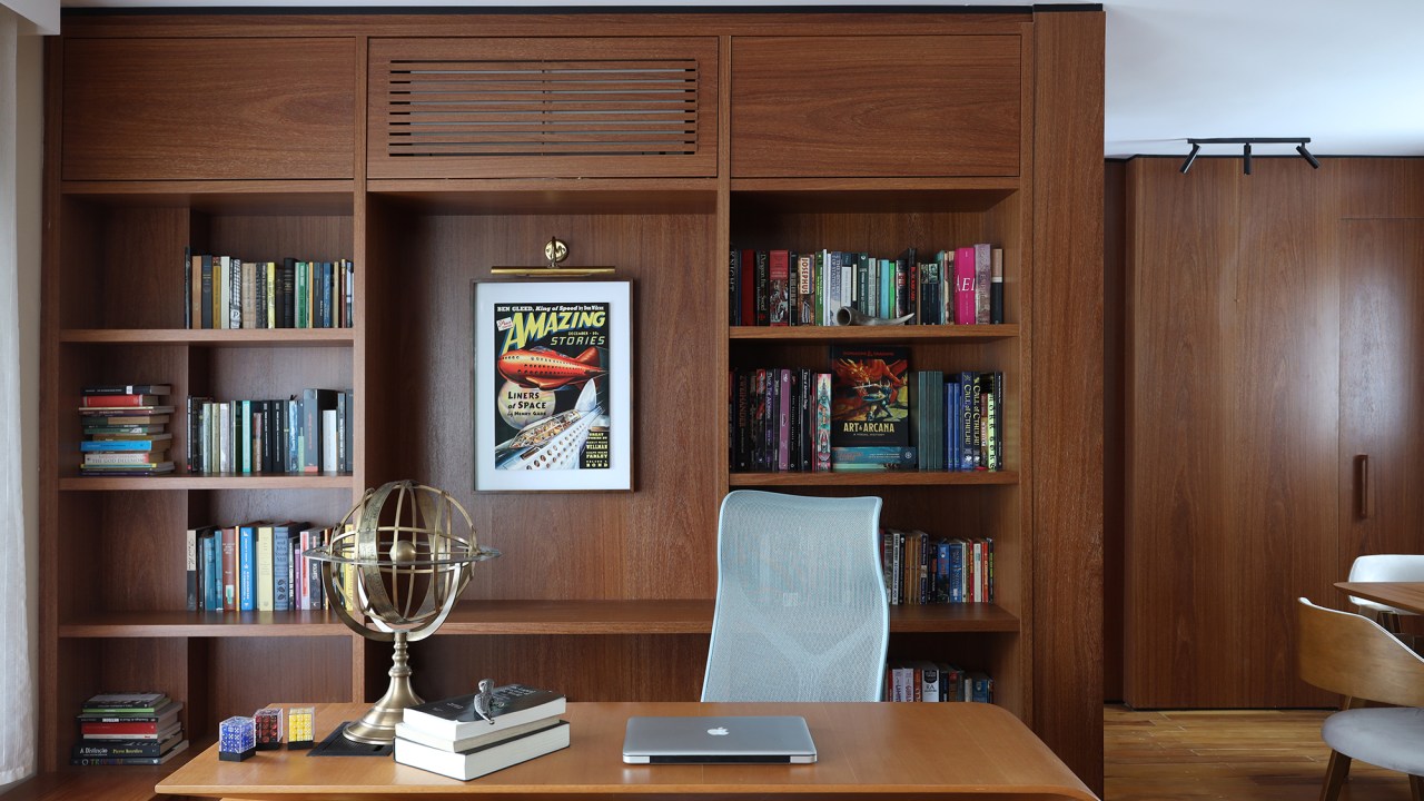 Peças retrôs e décor futurista se encontram no apartamento de 90 m². Projeto Trees Arquitetura. Na foto, home office com móveis de madeira.