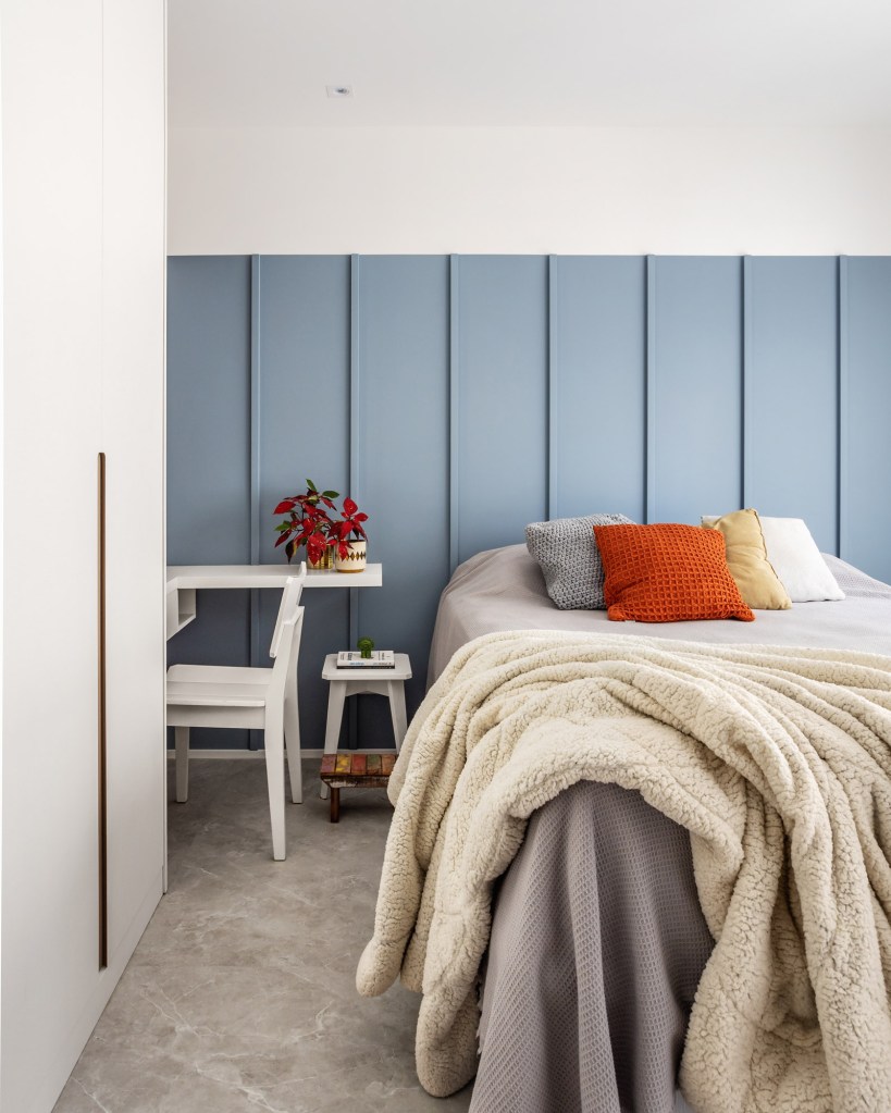 Quarto com armário branco, cama de casal e cabeceira de madeira azul.