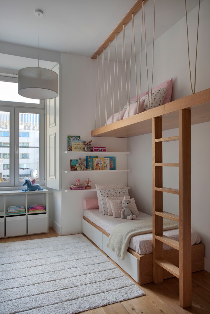 Quarto infantil com beliche, tapete claro e prateleira para livros.