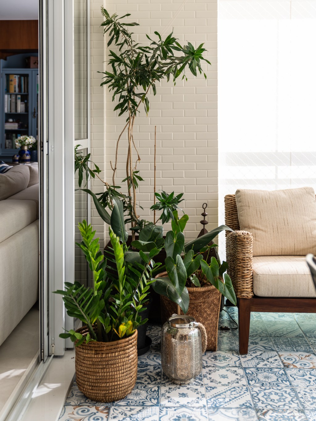 Apê de 194 m² tem cara de casa e é repleto de arte étnica. Projeto de Lovisaro Arquitetura. Na foto, varanda com poltrona, plantas e piso estampado.