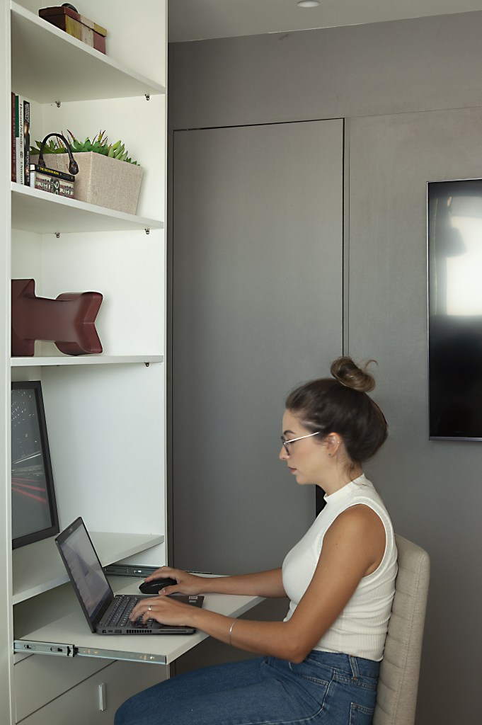 Home office com bancada retrátil em estante branca.