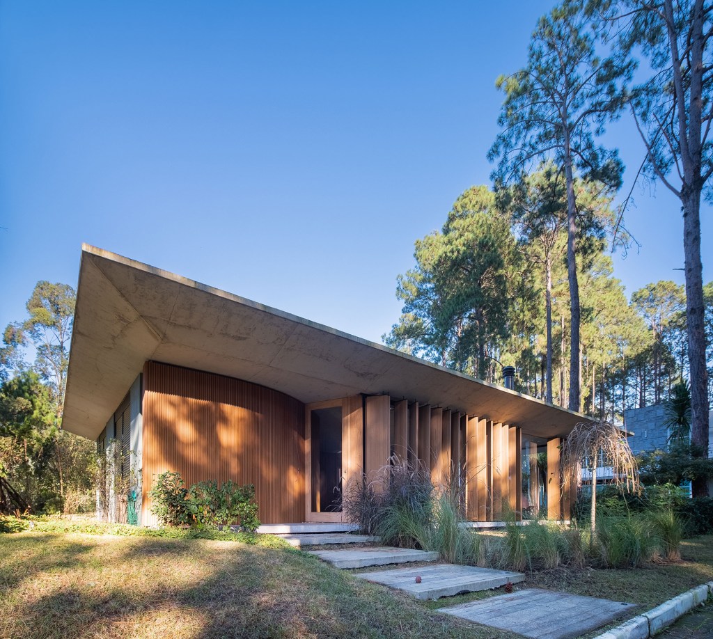 Layout minimalista marca casa térrea de 201 m² no Rio Grande do Sul. Projeto de Stemmer Rodrigues Arquitetura. Na foto, fachada da casa em meio ao jardim.