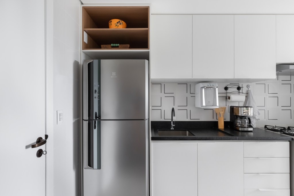 Cozinha com marcenaria branca e backsplash de azulejos.