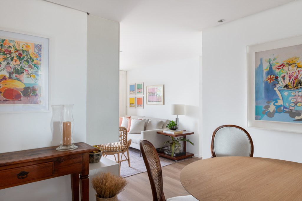 Sala de jantar com mesa redonda de madeira, cadeiras e aparador de madeira.