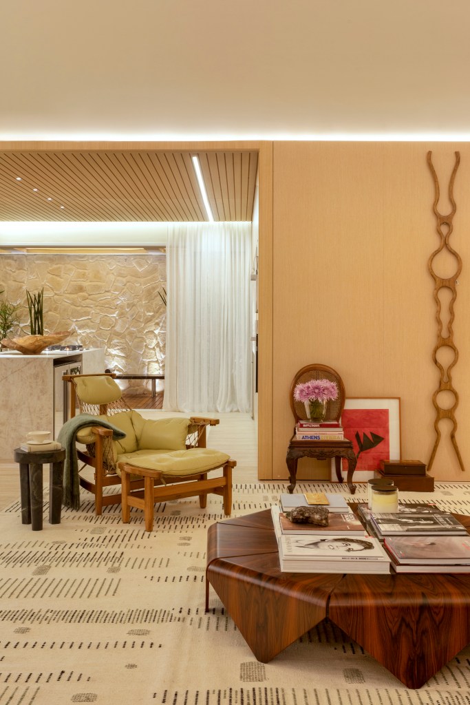 Quiet luxury e feng shui indiano marcam este loft de 120 m², Projeto de Bianca Da Hora Arquitetura para a CASACOR SP 2023. Na foto, sala de estar com mesa de centro, poltrona, tapete e cozinha integrada.