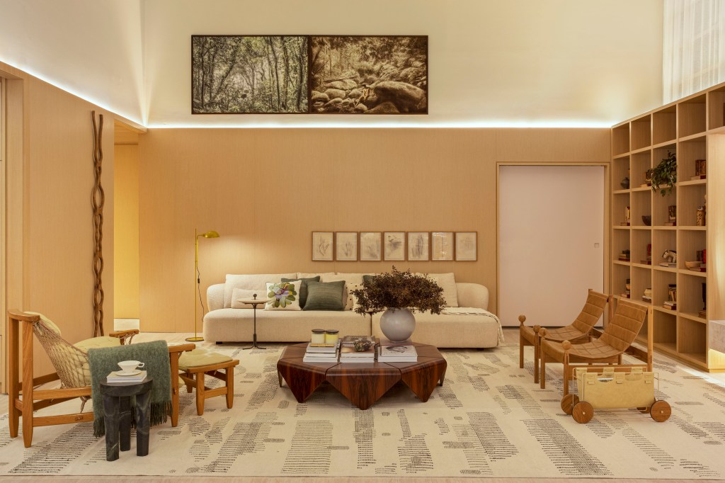 Quiet luxury e feng shui indiano marcam este loft de 120 m², Projeto de Bianca Da Hora Arquitetura para a CASACOR SP 2023. Na foto, sala de estar com meia-parede, quadros, estante e sofá.