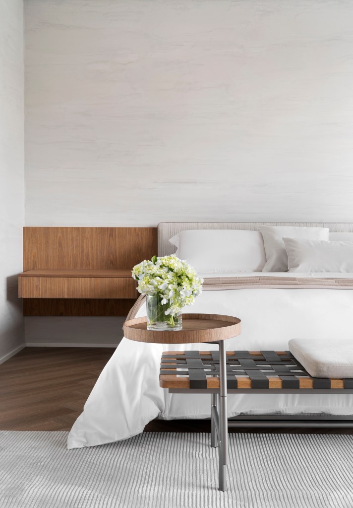 Quarto minimalista com parede cinza clara, cama de casal e cabeceira de madeira