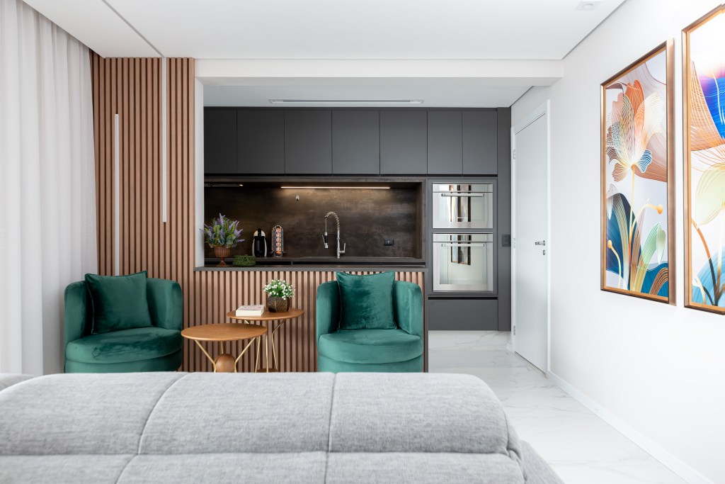 reforma-ape-home-office-varanda-banheiro-preto-marmorizado-palladino-arquitetura-12 Projeto de Palladino Arquitetura. Na foto, cozinha integrada com marcenaria cinza, piso de porcelanato e sala com poltronas verdes.