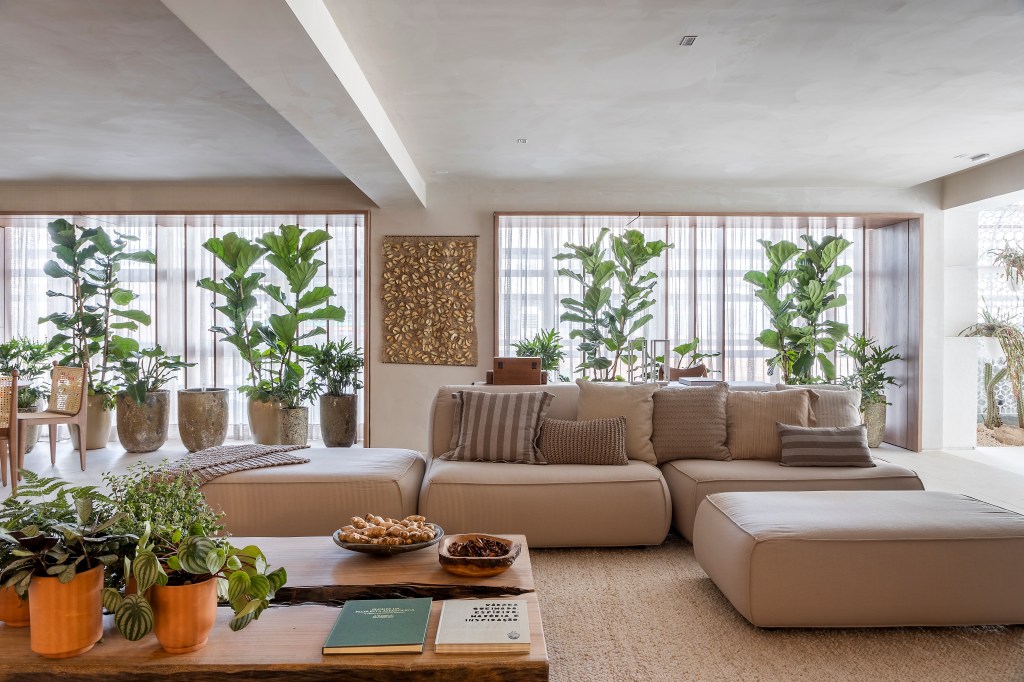 slow-living-sala-estar-refugio-materiais-naturais-artesanato-isabela-nallon-casacor-sp-2023-18 Sala de estar com tons beges claros, sofás beges, vasos com plantas grandes.