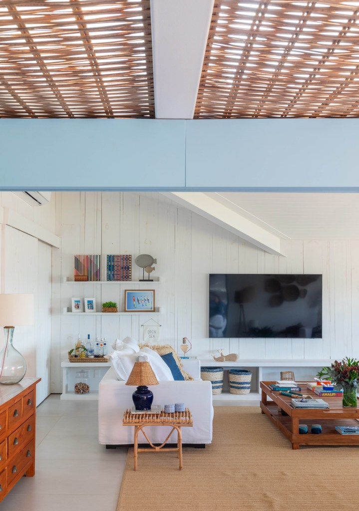 casa-de-praia-inspiracao-grega-area-gourmet-24m-brise-arquitetura-17-sala Projeto de Brise Arquitetura. Na foto, sala com paredes brancas, ventilador, cestarias nas paredes, sofá branco e tapete bege.