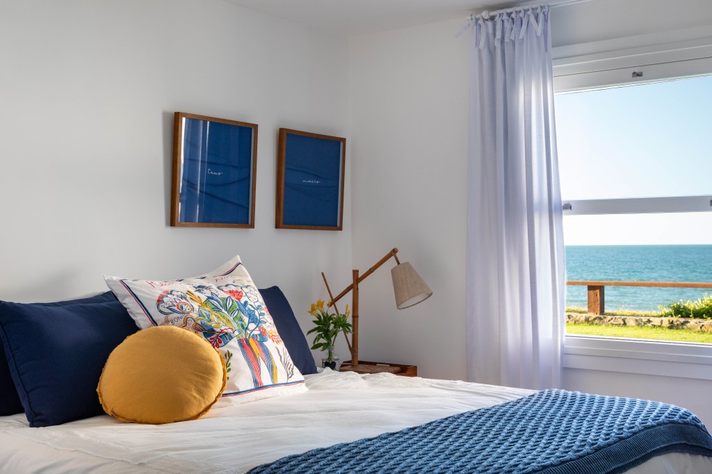 casa-de-praia-inspiracao-grega-area-gourmet-24m-brise-arquitetura-27-quarto Projeto de Brise Arquitetura. Na foto, quarto com cama de casal, cortina branca e vista para praia.