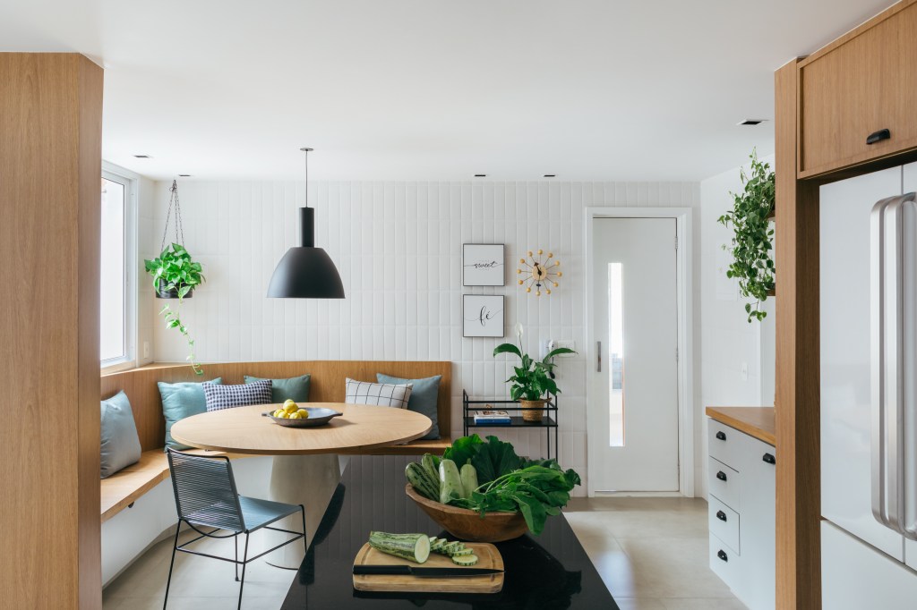 Cozinha com copa de 28m² tem mesa redonda e canto alemão de banco curvo