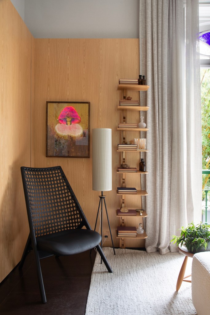 madeira-design-brasileiro-quarto-de-hotel-studio021arquitetura-casacor-rio-2023-07 Quarto 021 - Projeto do Studio021 Arquitetura para a CASACOR Rio 2023. Na foto, quarto com cadeira preta e estante pequena.