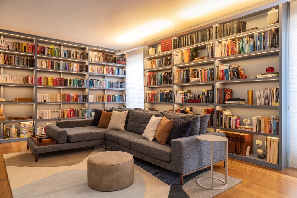 Projeto de Stal Arquitetura. Na foto, sala de estar com biblioteca. Estante de marcenaria em tom azul.