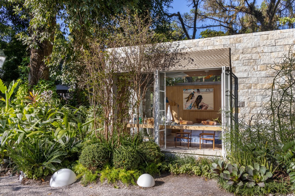 materiais-naturais-pedras-brasileiras-bangalo-29m-adriana-esteves-03 Na.Morada - ambiente de Adriana Esteves para a CASACOR Rio 2023. Na foto, fachada do bangalô com jardim em volta.