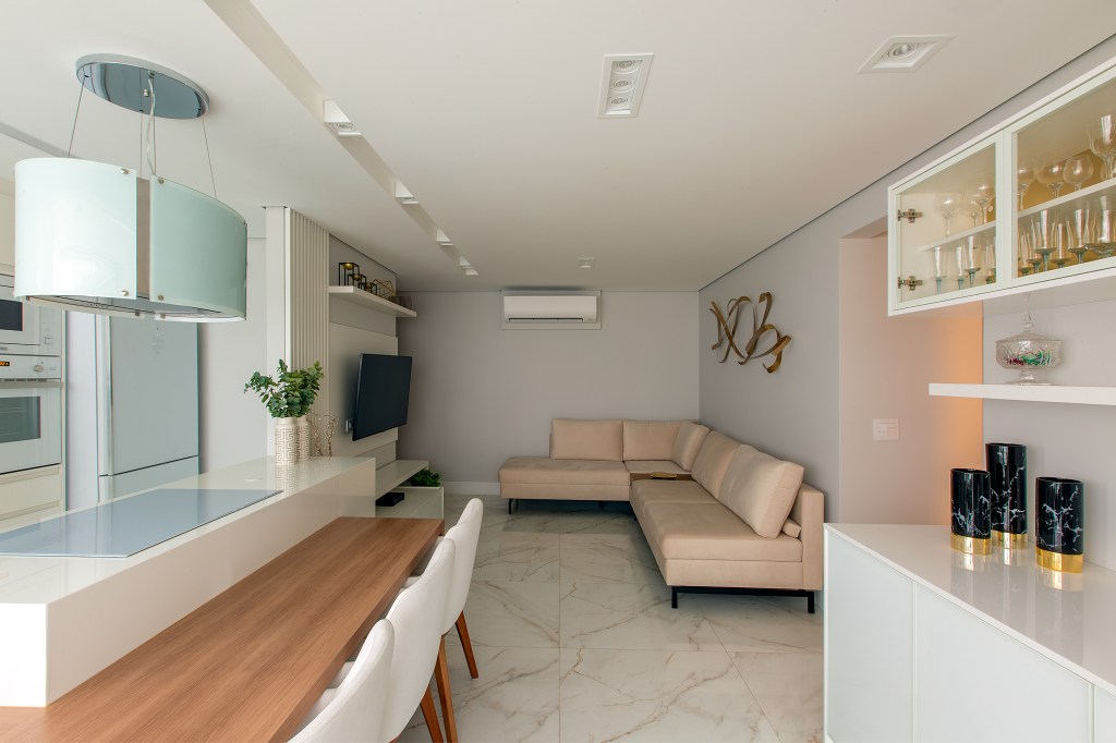 nape-83m-paleta-branca-metais-dourados-luciana-patriarcha-09 Projeto de Luciana Patriarcha. Na foto, sala com piso frio, sofá em L e cozinha integrada.