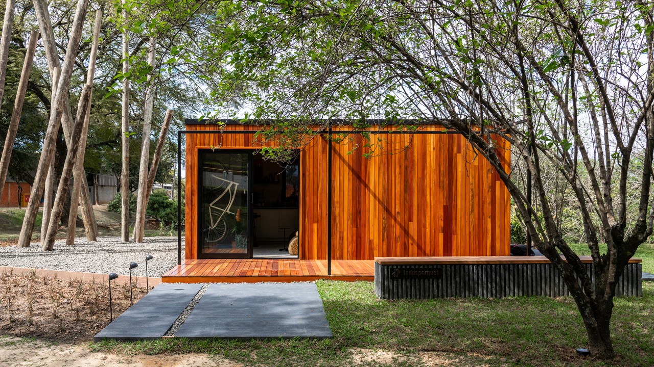 Tiny house sustentável de madeira fica pronta em 1 mês. Na foto, fachada de madeira da casa no meio do jardim.