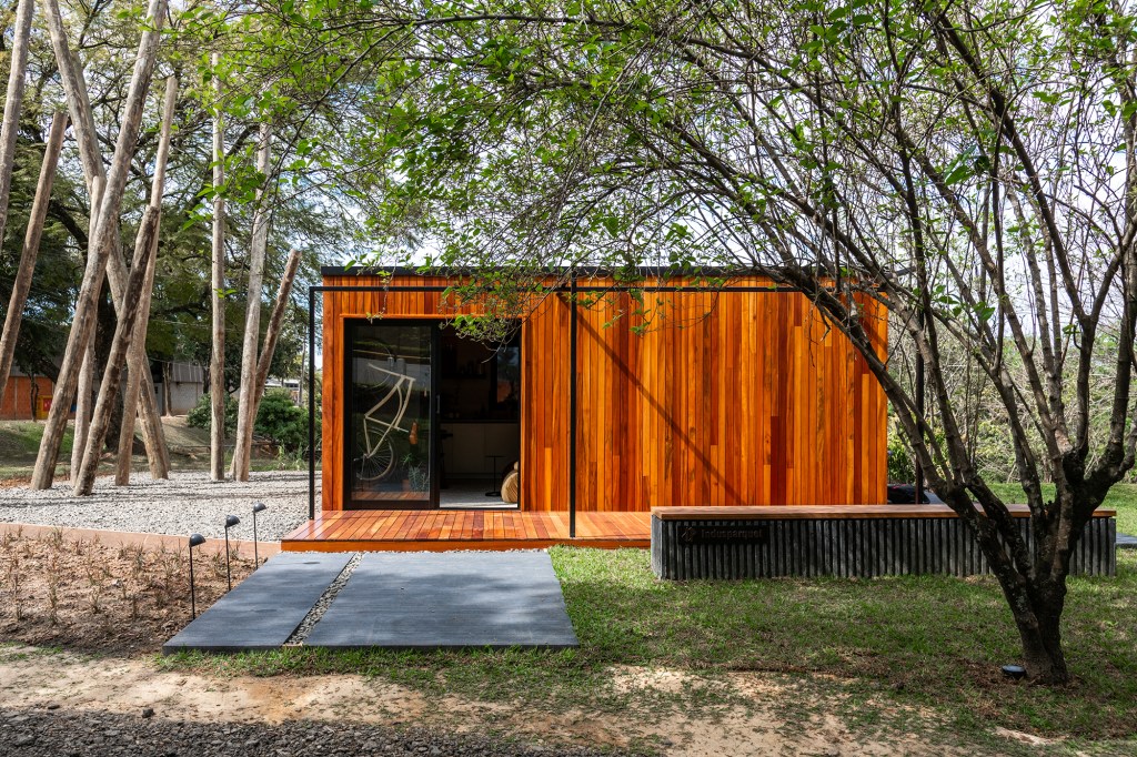 Tiny house sustentável de madeira fica pronta em 1 mês. Na foto, fachada de madeira da casa no meio do jardim.