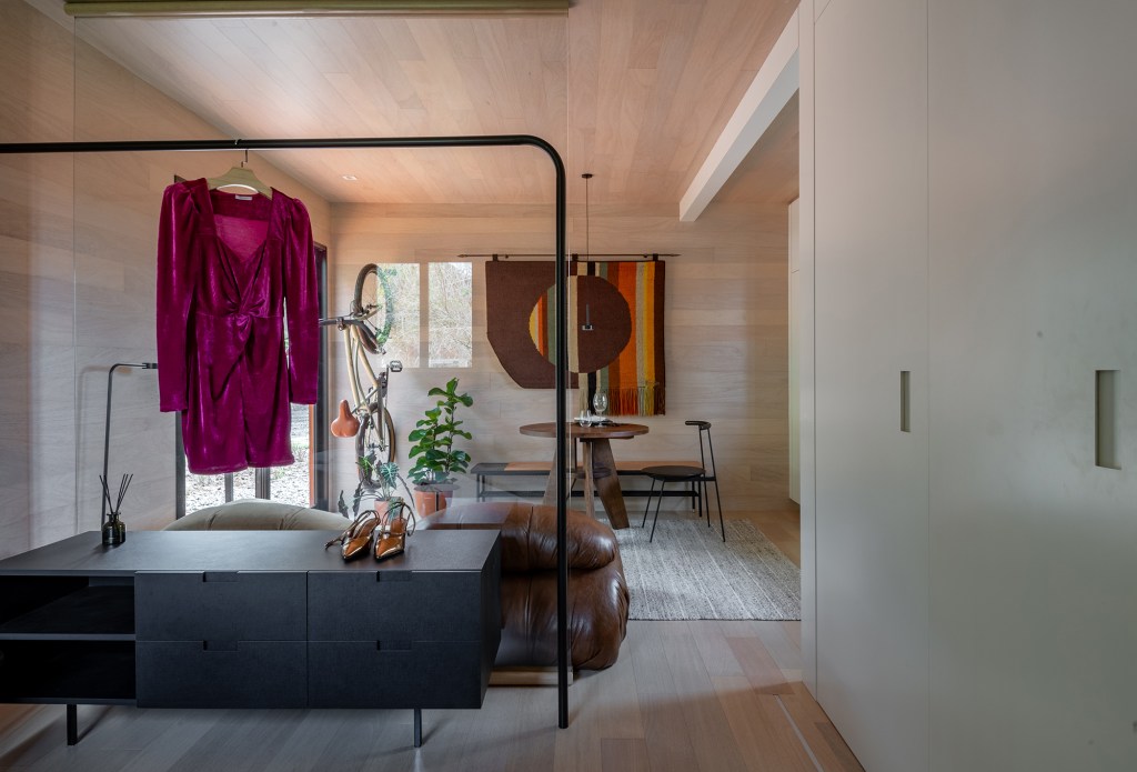 tiny-house-sustentavel-madeira-pronta-em-1-mes-credito-favaro-jr (18) Tiny house sustentável de madeira fica pronta em 1 mês. Na foto, sala de estar com tapecaria na parede, mesa e plantas.