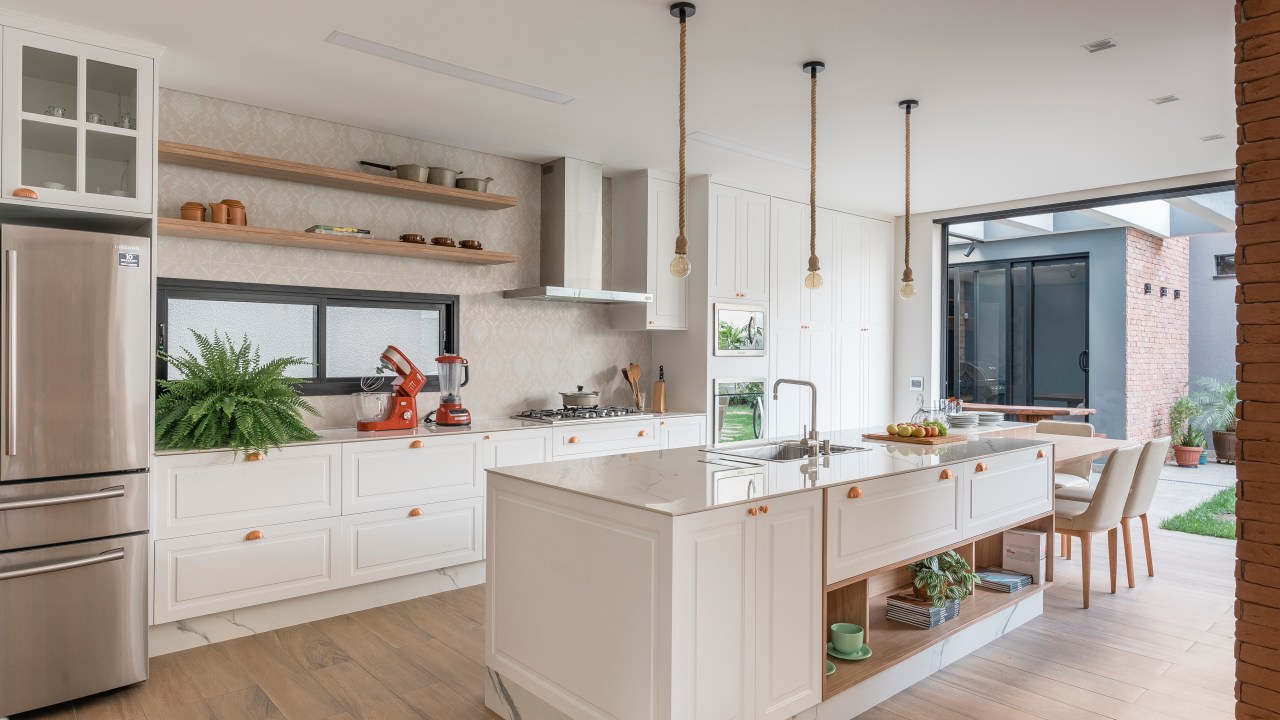 Projeto de PB Arquitetura. Na foto, cozinha em estilo shaker com ilha branca e marcenaria branca.
