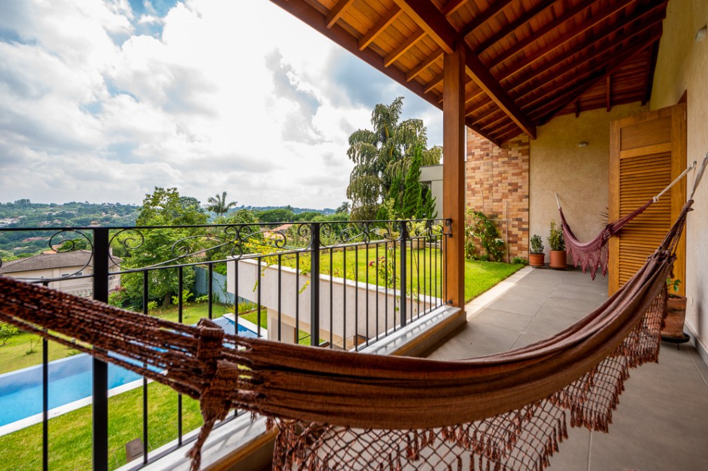 Casa de campo de 450 m² tem dois estúdios e vista para a natureza. Projeto de Geração Arquitetura. Na foto, varanda com rede e vista para o jardim.