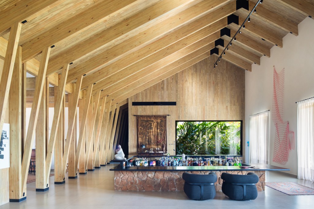 Casa celeiro de madeira une o rústico e o moderno em projeto de 1230 m². Projeto de Otto Felix. Na foto, sala de estar com paredes de madeira e bar.