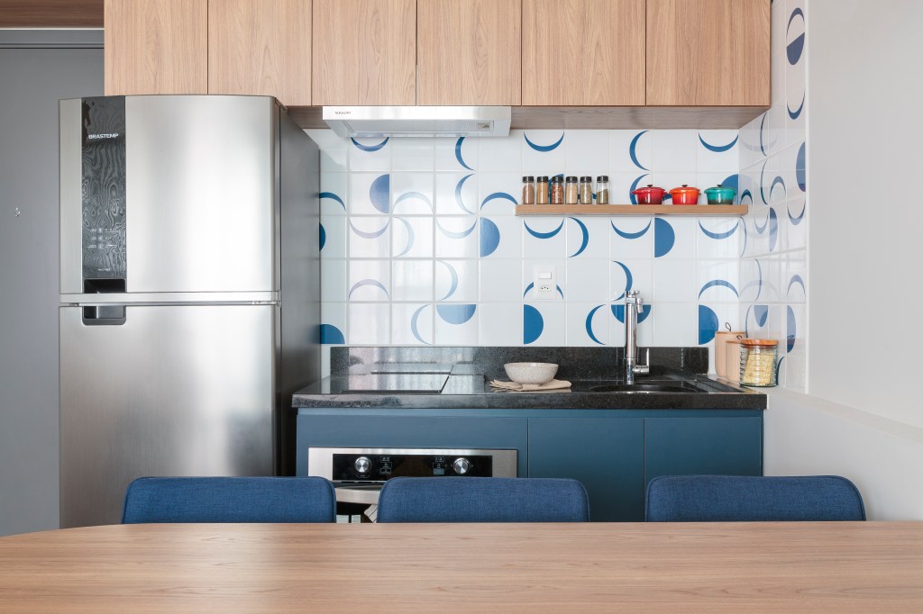 tons-azul-amarelo-ape-compacto-42m-estudio-mare-03-cozinha-azulejo Projeto de Estúdio Maré. Na foto, cozinha integrada com parede de azulejos e bancada com cadeiras azuis. Marcenaria azul.