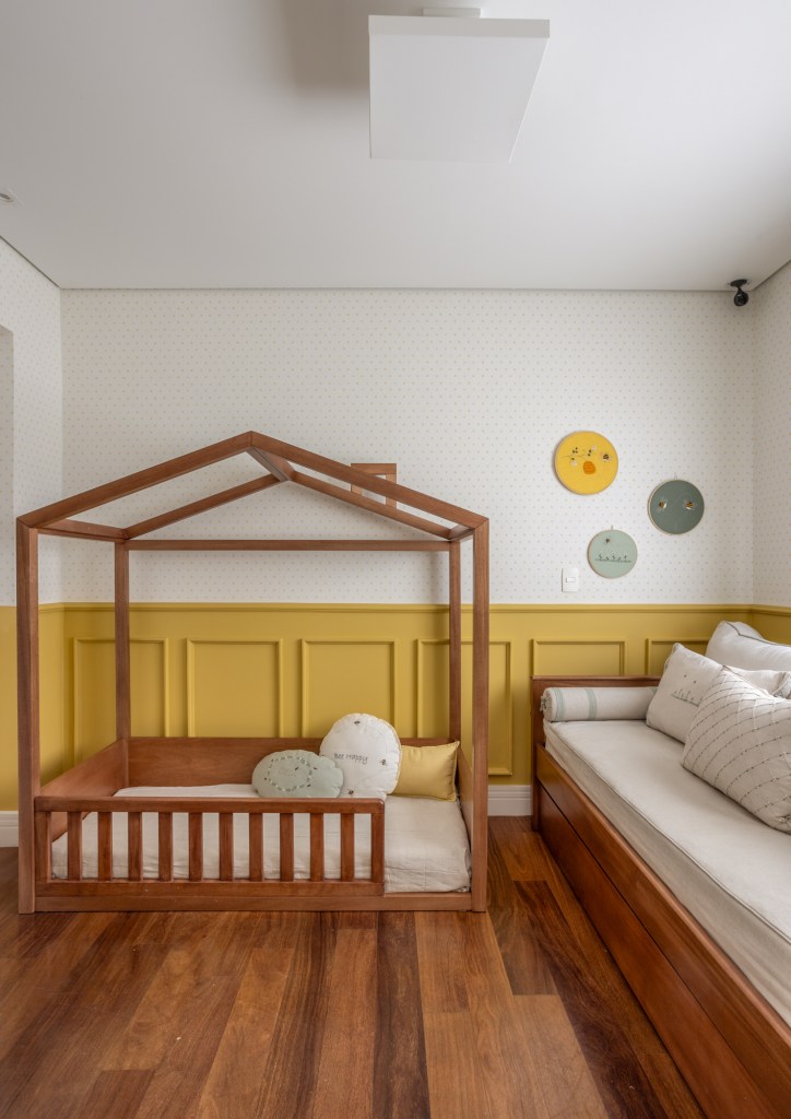 Apê garden tem academia compacta e varanda com gramado e muitas plantas. STAL Arquitetura. Na foto, quarto infantil com cama de casinha, meia parede amarela e boiseries.