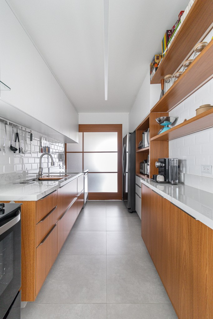 cozinha-minimalista-pensada-abrigar-utensilios-inovando-arquitetura-01 Cozinha minimalista foi pensada para abrigar muitos utensílios. Projeto de Inovando Arquitetura. Na foto, cozinha com piso de porcelanato, armários em madeira e bancada branca.