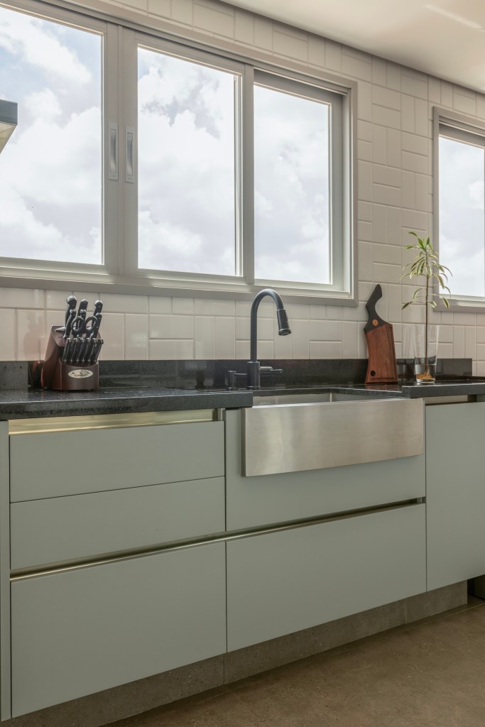 Reforma transforma apartamento de 362 m² em refúgio urbano minimalista. Projeto Inovando Arquitetura. Na foto, cozinha com farm sink de inox e marcenaria verde.